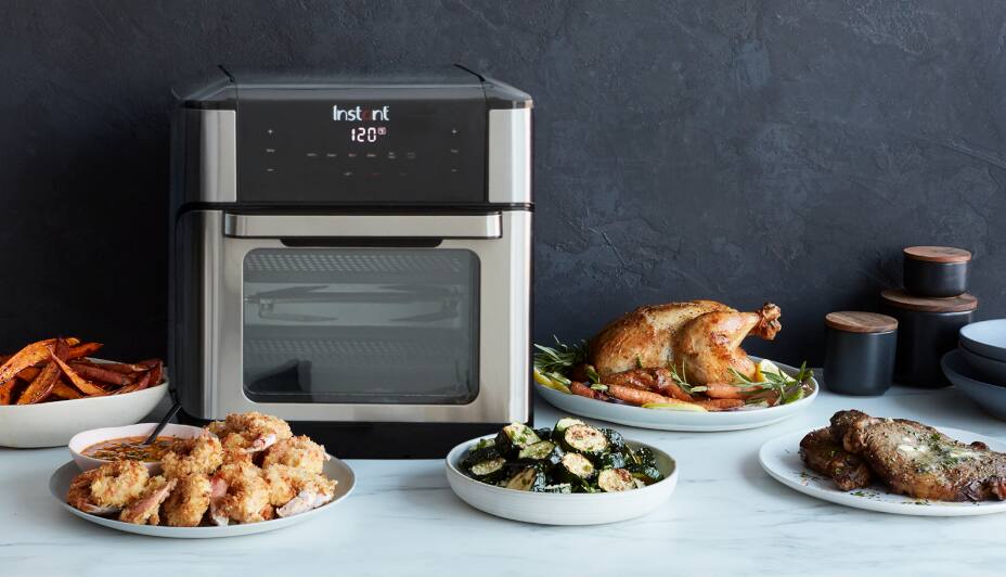 Instant Pot Vortex Plus Convection Air Fryer Oven rests on a counter with several dishes of food.