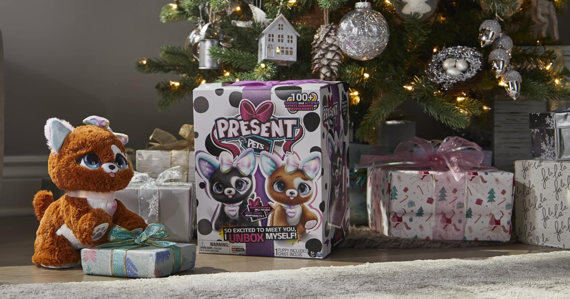A Present Pets plush toy and package under a tree with wrapped gifts. 