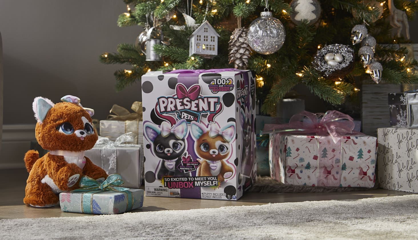 Un jouet en peluche Present Pets et un emballage sous un arbre avec des cadeaux emballés.