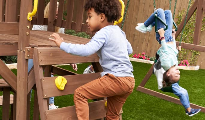 Children playing on a wooden Kid Kraft Arbour Crest Play Centre.