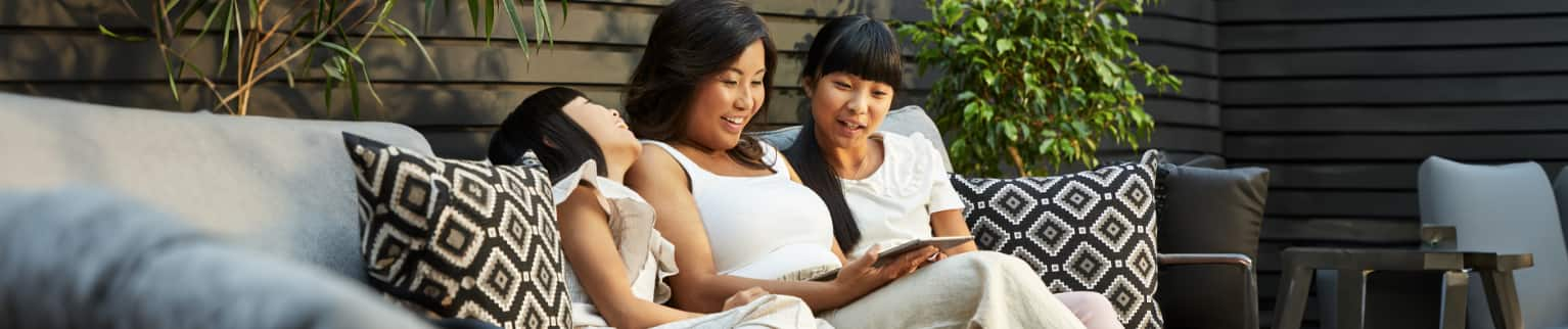 Two women and a child relaxing on a patio sofa. 