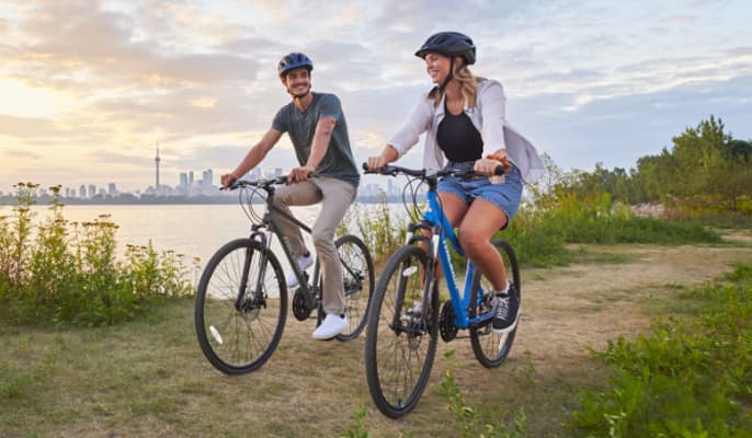 Two adults with bikes and helmets on an outdoor trail.