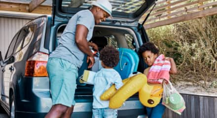 A family packs beach-day essentials into the trunk of a car.